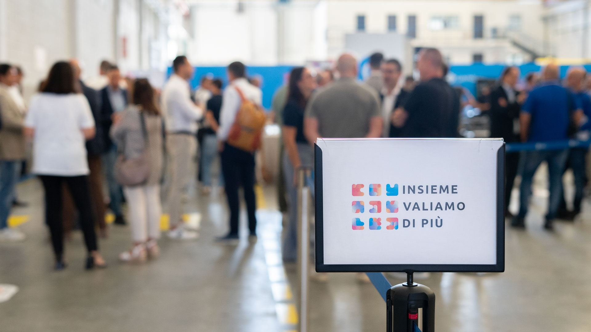 Cartello Insieme valiamo di più all'ingresso dello stabilimento 2 di Gambini, con gli ospiti dell'Evento Fornitori sullo sfondo