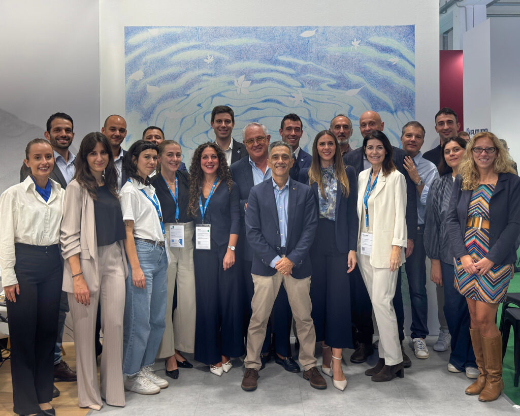 Il team Gambini davanti al murale dello stand al MIAC 2026