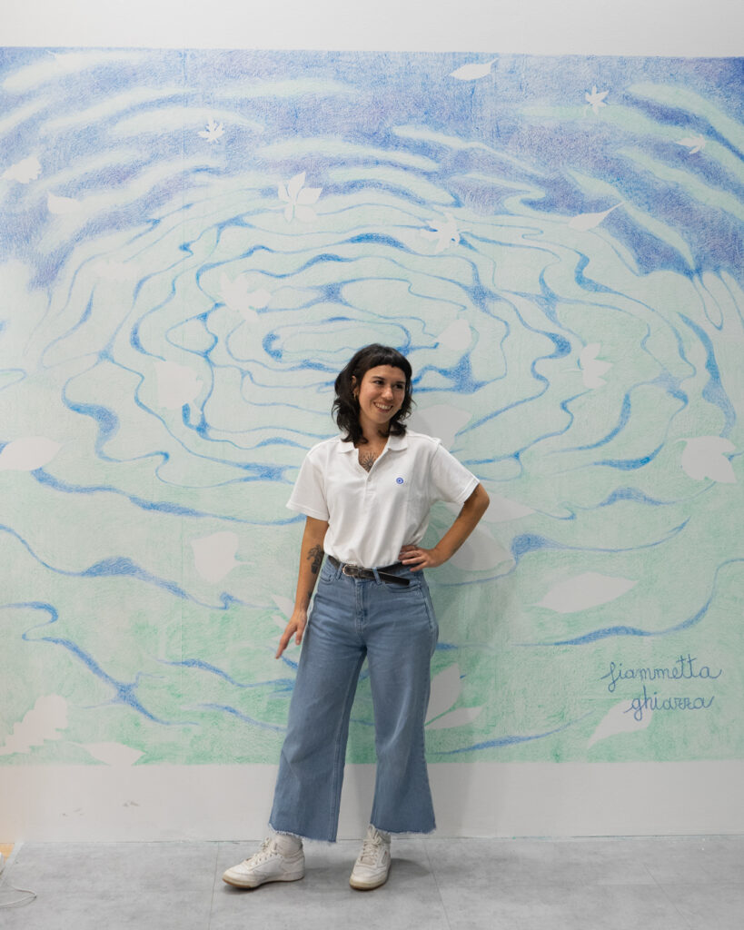 L'artista Fiammetta Ghiazza davanti al murale sull'acqua realizzato dal vivo allo stand Gambini al MIAC 2026